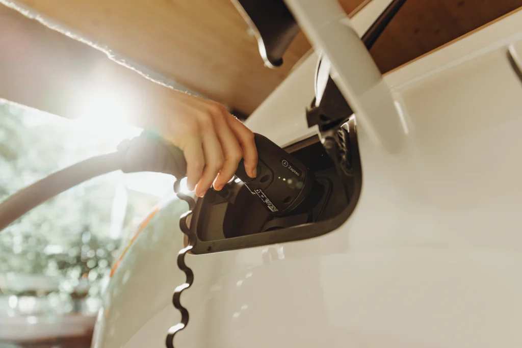 Driver plugging a charging cable into a white electric vehicle